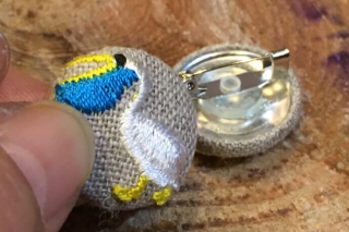 ペリカンの刺繍くるみボタンをブローチに加工した例